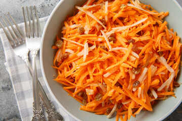 Crispy vegan carrot apple salad with raisins close-up in a bowl on the table. horizontal top view from above