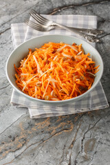 Raw carrot apple salad with raisins close-up in a bowl on the table. vertical
