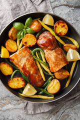 pork tenderloin in lemon garlic marinade baked with potatoes and green beans close-up in a frying pan on the table. Vertical top view from above