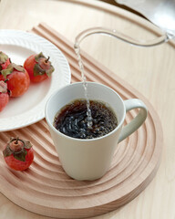 Hot Coffee Being Poured into Mug with Persimmons on Wooden Tray, A cup of black coffee with persimmon on a wooden table