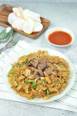 Char Kway Teow, fried rice flat noodles with beef, egg, and vegetables on a white plate, Indonesian dish.