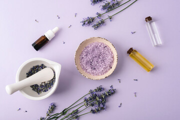 Lavender spa composition with sea salt, essential oils and mortar on pastel background. Top view, flat lay
