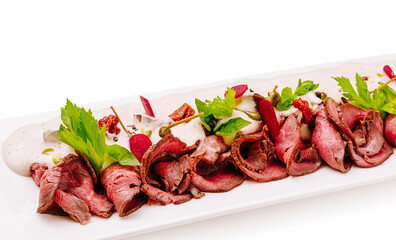 Delicious roast beef platter with fresh herbs and sauces at a dining table