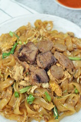 Char Kway Teow, fried rice flat noodles with beef, egg, and vegetables on a white plate, Indonesian dish.