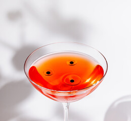 Vibrant cocktail with black garnish on a minimalistic background