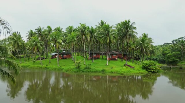 From the front of a tranquil lake in Laguna, the camera moves upward and forward, highlighting traditional bahay kubo houses and the surrounding greenery.