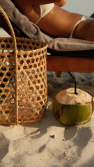 Tropical beach relaxation with fresh coconut drink and straw basket on white sand