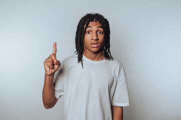 portrait of young individual raises a finger in a thoughtful gesture, symbolizing the importance of focus on light background