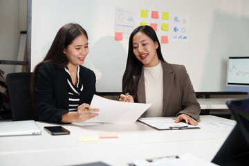 Businesswomen working together, analyzing financial documents in office