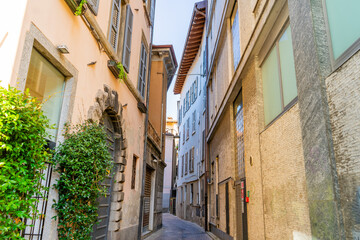 Paving stones empty narrow Italian street in Como city. Multicolor old house building architecture. Medieval village facade