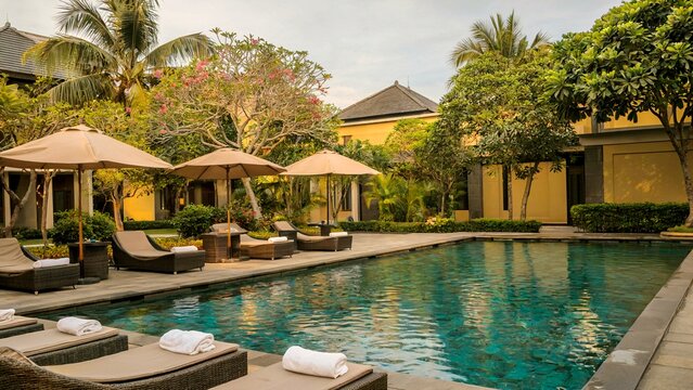 Sunny Poolside Resort Courtyard With Lounge Chairs, Umbrellas, and Palm Trees