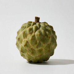 Fototapeta premium A green custard apple with a textured polygonal surface and darker ridges at junctions, featuring a brown stem,