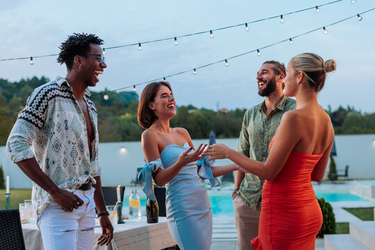 Friends laughing together at a pool party, enjoying summer evening