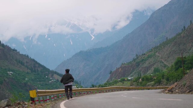 Defocused Indian man running in front of Himalayan mountain ranges covered by clouds during the monsoon season near Udaipur in Pattan Valley, Lahaul, Himachal Pradesh, India. 