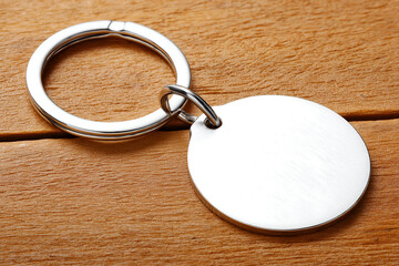 Round Silver Keychain on Wood Background with Metallic Ring. Mock up promotion information for marketing announcements and details, blank white space.