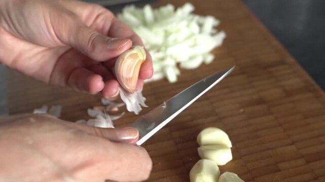 Female hands peeling a clove of garlic. Close-up.