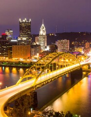 Fototapeta premium Night cityscape with illuminated bridge and river reflections