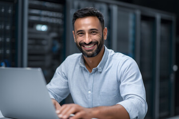 Indian IT engineer working on laptop in server room for system maintenance