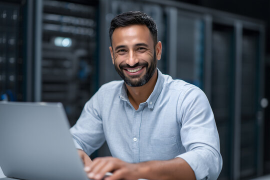 Indian IT engineer working on laptop in server room for system maintenance
