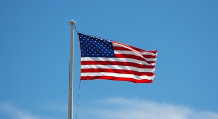 Obraz premium American flag waving in the wind against a clear blue sky on a sunny day