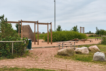 Community playground with wooden climbing frames, balance beams and picnic tables © VeugerStock