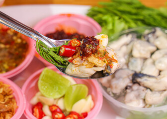Spicy Oyster with Chili and Herbs on Spoon.