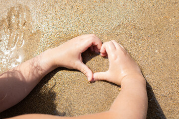 Hands forming a heart on the beach