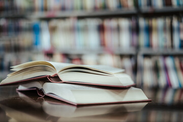 Open book with books piled up on the table in the library. Basic education concept.