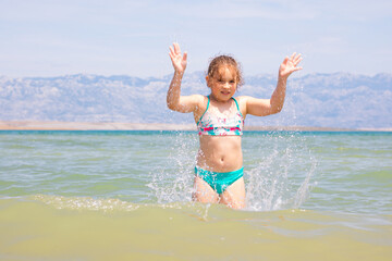 Young girl splashing in water at the beach