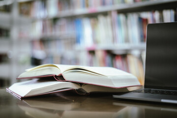 Open book with books piled up on the table in the library. Basic education concept.