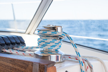 Sailboat winch on a sailing boat and ropes at stoppers, line jammer. Yachting details of rigging on a sailboat