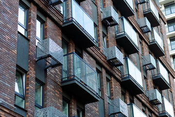 A modern residential building with a brick facade, glass balconies and metal air conditioning grilles. The elegant design emphasizes the style of urban architecture.