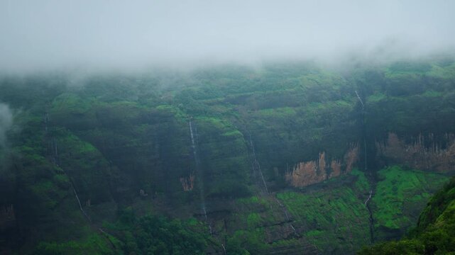 4K shot of small waterfalls during the rainy season at Western Ghats as seen from Savlya Ghat in Maharashtra, India. Scenic view of waterfalls flowing from the Sahyadri hills during monsoon season.