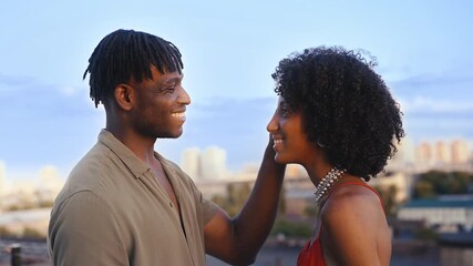 Loving man touching girlfriend's hair, talking during rooftop date at sunset - Powered by Adobe