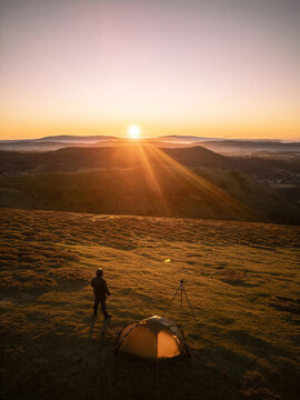 An explorer and his wild camping tent on a hill in England at sunrise