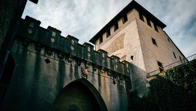 Ancient Stone Fortress Tower with Battlements and Archway Under Dramatic Sky