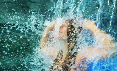 Veiled in a torrent of sparkling drops, sexy, nude, ginger woman stands under a waterfall, immersed in the wild intensity of water and emotion