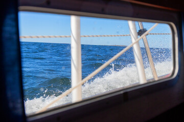 View through a boat porthole at rolling sea waves. A nautical perspective capturing motion, marine atmosphere, and connection to the ocean from inside the vessel
