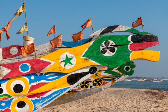 Colourfully decorated pirogue boats lined on a beach in Cap Skirring, Senegal
