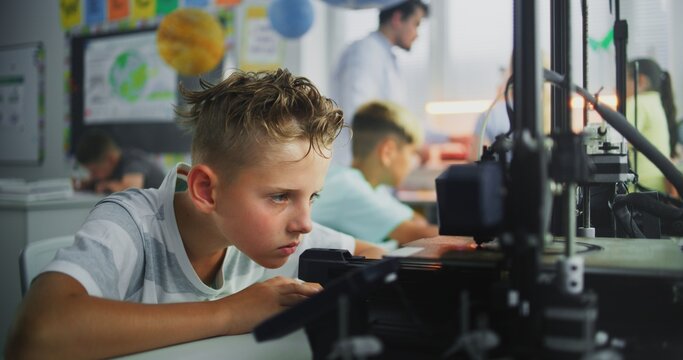 Talented Young Boy Using 3D Printer Touchscreen, Studying Advanced Automated 3D Printing. Primary School Student During Engineering and Programming Lesson in Classroom. Interactive STEM Education. - Powered by Adobe