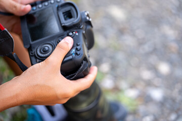 Photographer setting professional digital camera while working in nature
