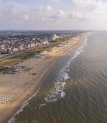 Aerial view of a beach and cityscape with Ferris wheel.