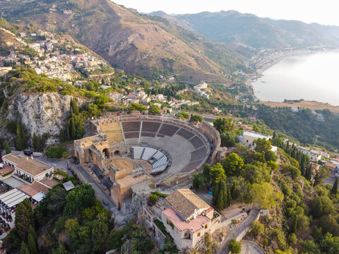 Aerial view of the ancient Teatro Greco amphitheater standing majestically against the backdrop of the Ionian Sea, bathed in the warm Sicilian sun, Taormina, Sicilia, Italy.