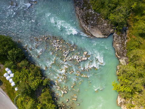 Aerial view of the glacial river, Stardalselva, flowing around rocks and banks of green vegetation with a road next to it, Stardalen, Vestland, Norway.