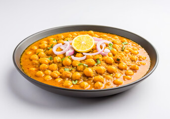 Delicious Chana Masala, a popular Indian chickpea curry, garnished with fresh onion, lemon, and cilantro, served in a dark bowl on a white background.