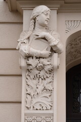 A beautiful Art Nouveau facade sculpture of a young womanThe detailed figure, with long hair cascading over her shoulders, rests on an ornate corbel