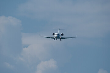 Airplane in the blue sky with white clouds and landing gear. The private plane is preparing to land at the airport on a sunny day.