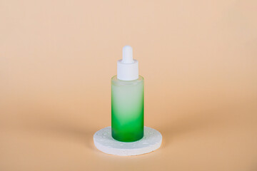 Green glass cosmetic bottle, Skin care or sunscreen cosmetic with stylish props on cream background.