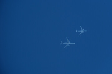 Two airplanes are flying in a clear blue sky on parallel courses.