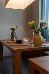 Dining table set with vases of flowers and candles in a cozy interior
